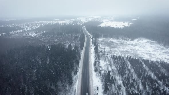 Aerial view of a wild winter forest and road. Beautiful road in the winter snowy forest.