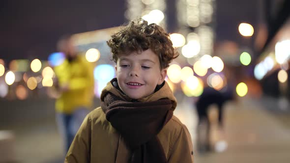 Charming Curly Little Boy is Strolling in City in Evening Portrait of Funny Toddler