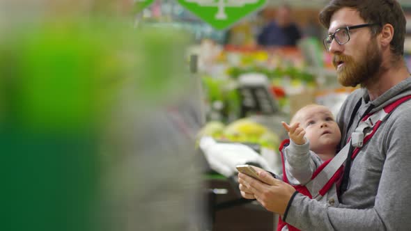 Man with Child Using Smartphone at Supermarket