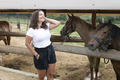 Placeit - Beautiful Young Woman in Countryside at a Horse Farm and Posing in Front of a Pony Horse - PhotoDune Item for Sale