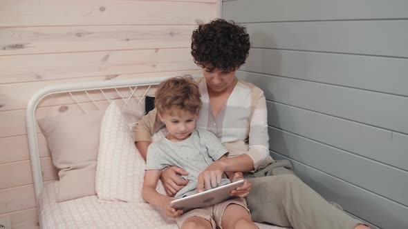 Happy Mother and Cute Boy Using Tablet in Bed