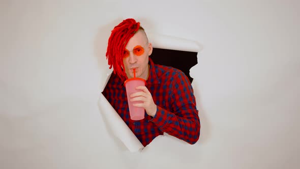 Young Man in Red Plaid Shirt Drinking Through Soft Drink Straw in Hole of White Background