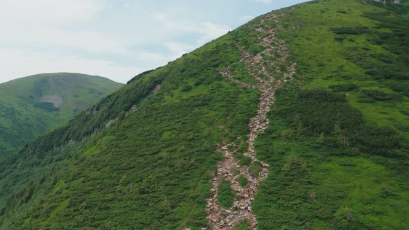 Aerial View of Young Hikers Walking Along a Mountain Trail to the Top of the Mountain