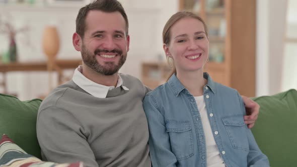 Happy Couple Smiling at the Camera While Sitting on Sofa