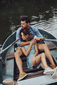  young couple embracing and looking away while enjoying romantic date on the lake