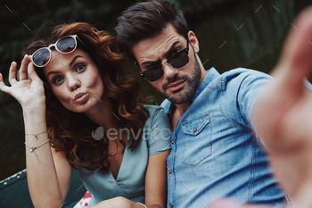 young couple looking at camera while sitting in the boat outdoors