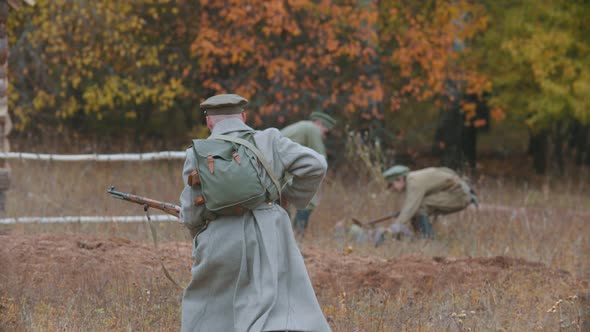 A Soldier Running on the Battlefield - Two Men Helping To Stand Up To Another Soldier