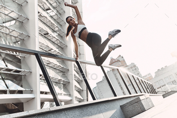 woman in sports clothing jumping while exercising outdoors