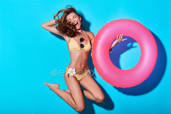 eping hand in hair and eyes closed while jumping against blue background