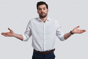 eping arms outstretched and looking at camera while standing against grey background