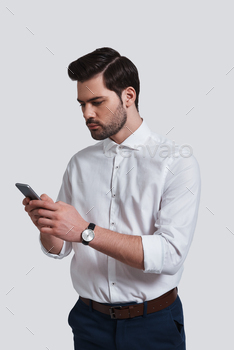 g his smart phone while standing against grey background