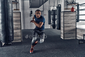 ome young African man in sport clothing running while exercising in the gym