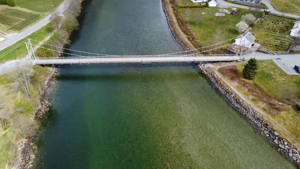 Old suspension bridge over river in Modalen Norway - Aerial fly over with tilt down