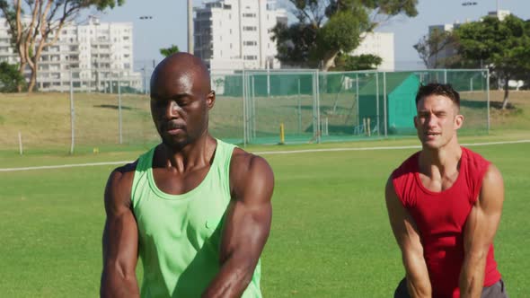 Diverse group of three fit men exercising outdoors, singing kettlebell weights