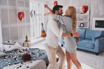 and smiling while standing in the bedroom full of balloons