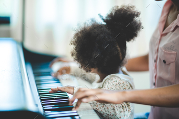 A girl practicing piano with her mother at home / Photodune, Misc