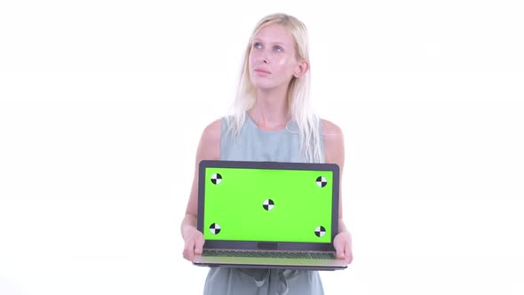 Happy Young Beautiful Blonde Woman Thinking While Showing Laptop