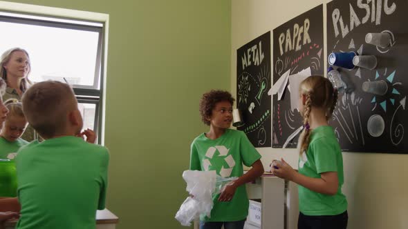 Two girls wearing recycle symbol tshirt holding plastic bottle and bag