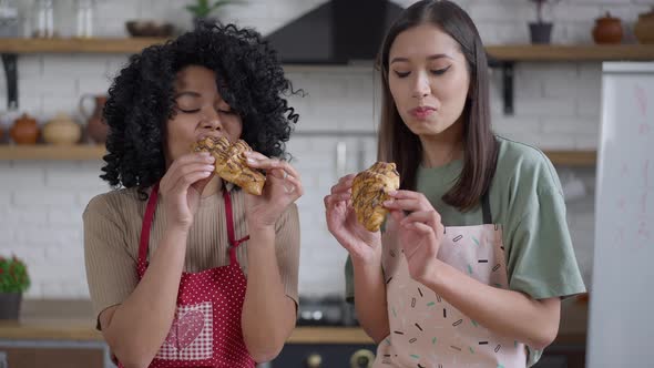 Live Camera Approaches to Joyful Slim Young Women Tasting Delicious Homemade Croissants in Kitchen