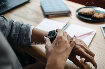 time productively and efficiently. Woman looking on alarm watch to managing time for organization of working process sitting in workplace.
