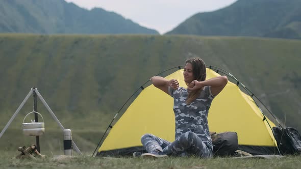 Girl Tourist After Sleep Pulls His Hands Up Sitting in Front of a Spider House in the Mountains