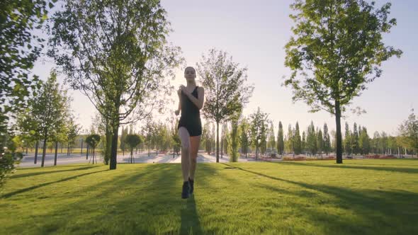 Sports Woman Makes Morning Jog and Physical Exercises In  Park