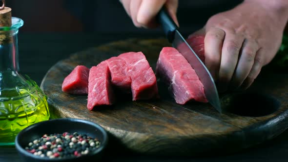 Man cut raw beef on steak pieces