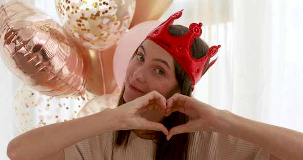 Woman in Crown Gesturing Heart During Party