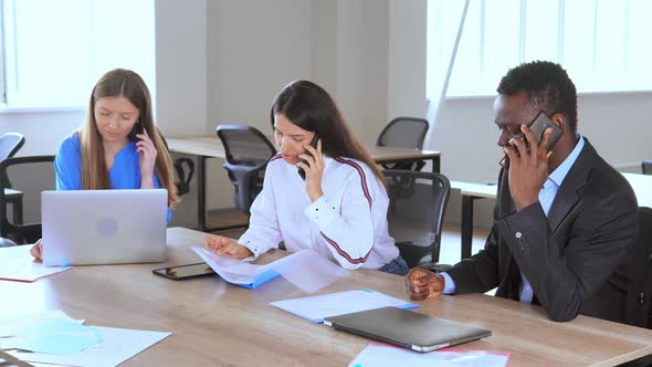 Staff Using Mobile Phones Talking with Clients Working Sitting at the Desk