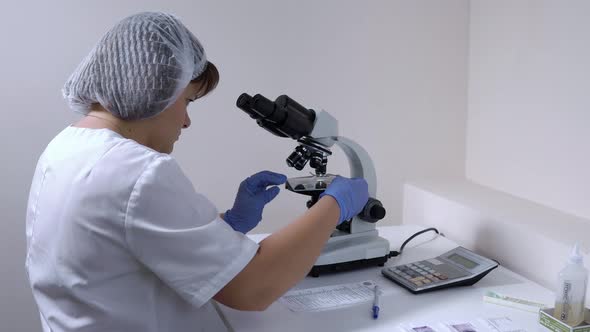 Woman Laboratory Assistant Moves the Slide and Analyzes the Biological Material