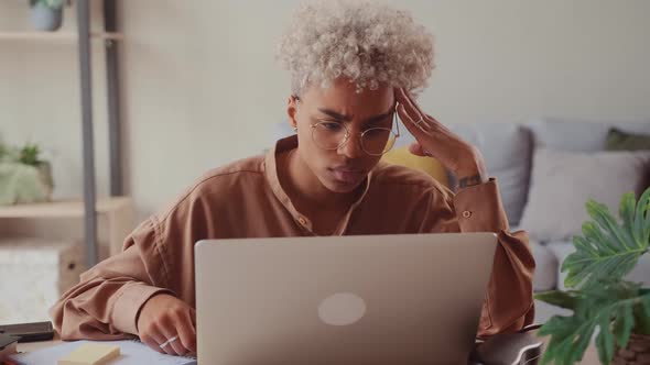 African Woman Looking at Laptop Work on Research Project Online on Computer