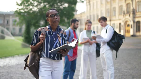 Portrait of Concentrated African American Woman Standing at College Campus Learning with Group of