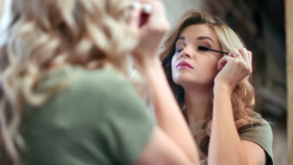 Beautiful Female Applying Mascara on Eyelashes Looking at Mirror