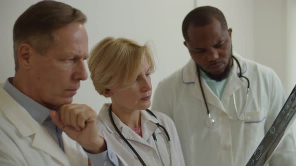 Portrait of Worried Puzzled Multicultural Physicians Examining Mri Scan at Medical Office