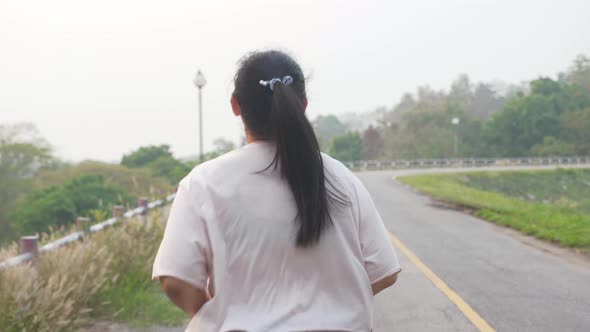 Rearview, close-up, follow shot of unrecognizable fat woman running outdoor