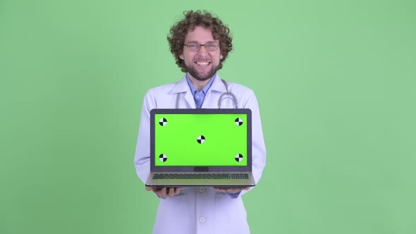 Happy Young Bearded Man Doctor Showing Laptop and Looking Surprised