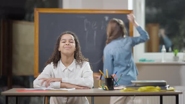 Middle Shot of Positive Confident African American Schoolgirl Posing in Classroom with Blurred