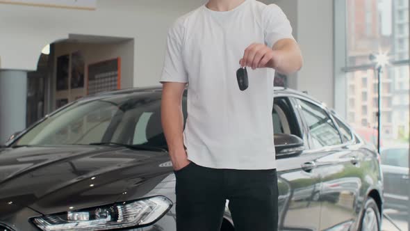 Cropped Shot of a Midsection of a Male Customer Holding Out Car Keys To His Newly Bought Car