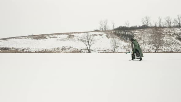 Fisherman with fishing equipment and ice drill