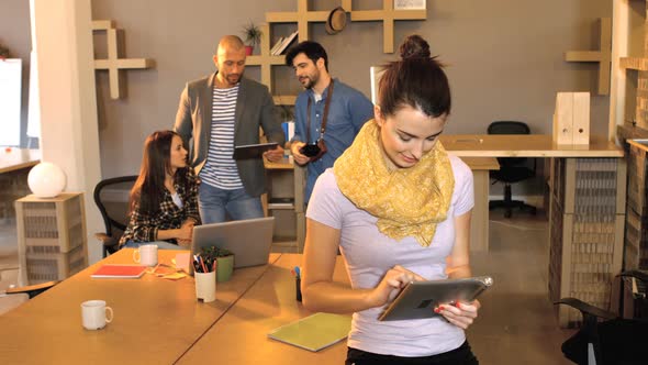 Female business executive using digital tablet while her coworker interacting in background