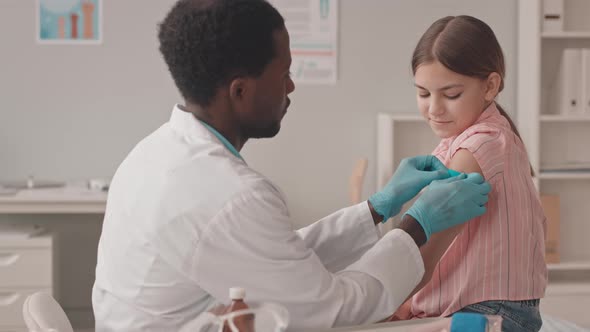 Doctor Putting Band Aid on Girls Shoulder after Injection