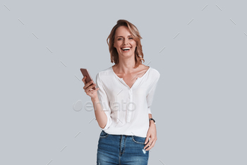 ooking at camera and smiling while standing against grey background