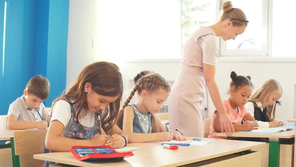 Teacher Helping Kids with Their Homework in Classroom at School