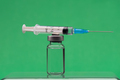 Syringe on top on a vaccine bottle, green background. - PhotoDune Item for Sale