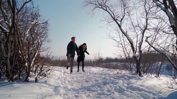 Happy Couple Running in Winter Forest