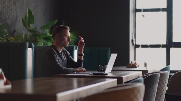 Thoughtful Serious Young Man Student Writer Sit at Home Office Desk with Laptop Thinking of