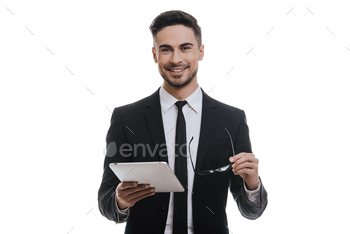 holding digital tablet and smiling while standing against white background