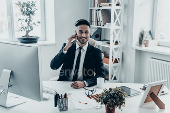 wear talking on the phone and smiling while sitting at the office desk