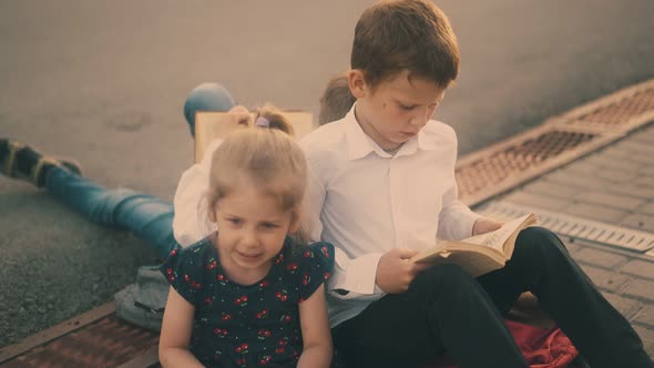 Young Naughty Girl Talks To Brothers Reading Books Close