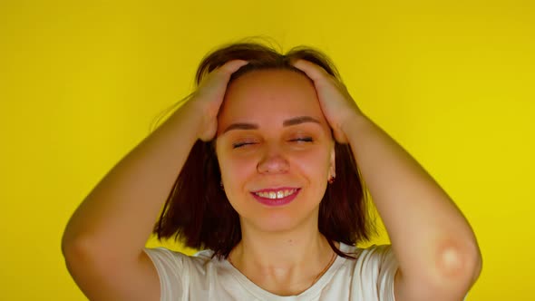 Close Up Young Woman Ruffles Her Hair on Yellow Background